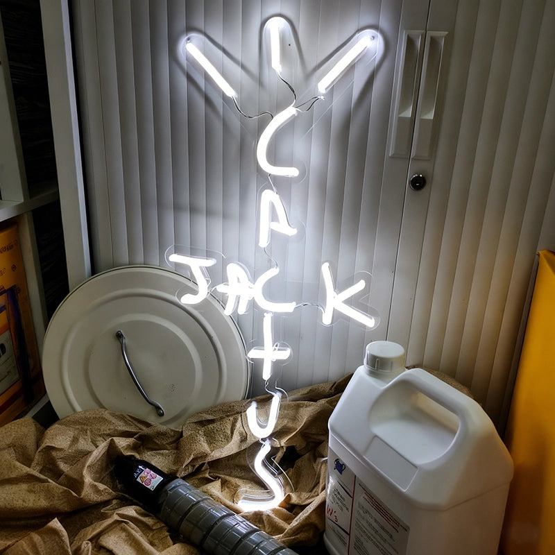 White Cactus Jack LED neon sign illuminated indoors, Travis Scott inspired neon wall light with acrylic backing for home, office, and entertainment room decor.