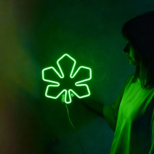 Person interacting with a glowing green neon sign shaped like a chestnut leaf on a dark background