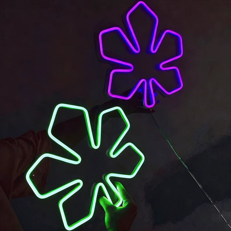 Two neon chestnut leaf shapes, one purple and one green, on a dark background.