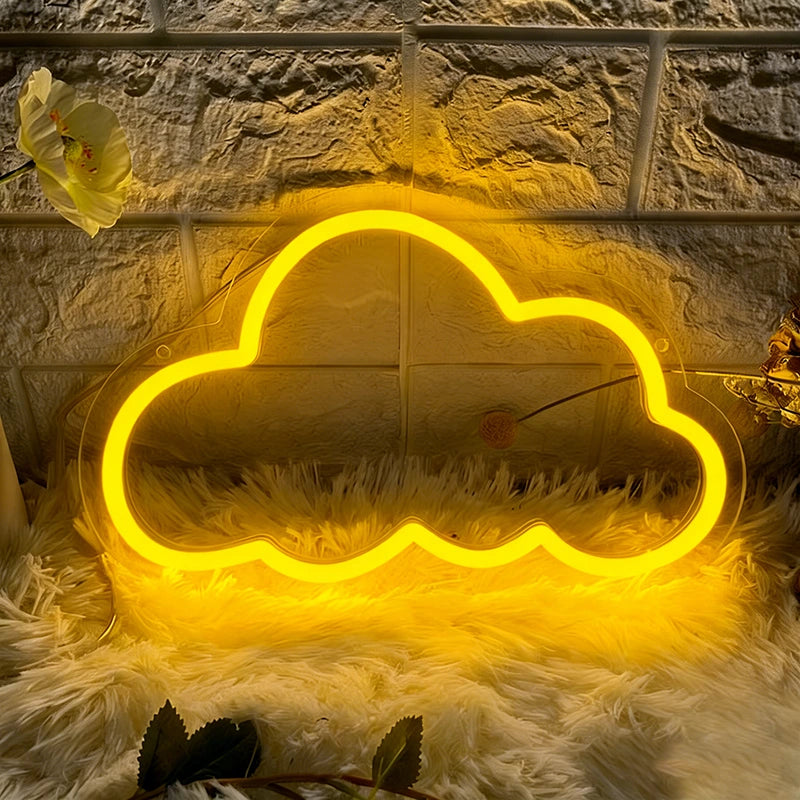 Yellow cloud-shaped neon light on a textured surface with a flower and green leaves.