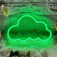 Green cloud-shaped neon light on a textured surface with a flower and green leaves.