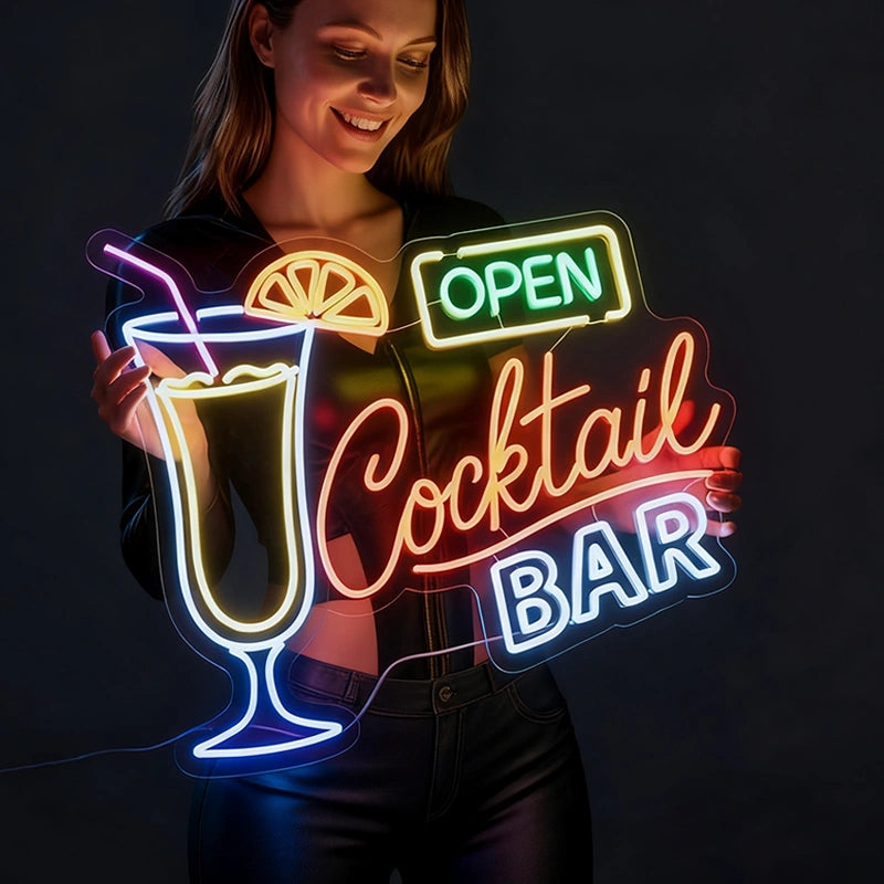 Neon sign of a cocktail glass with 'Open Cocktail Bar' text held by a person against a dark background