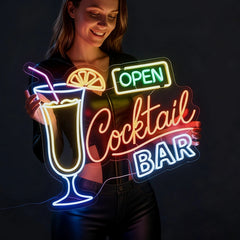 Neon sign of a cocktail glass with 'Open Cocktail Bar' text held by a person against a dark background
