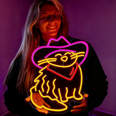 Person holding a neon sign of a cat in a cowboy hat against a purple background