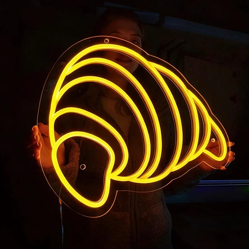 Person holding a glowing lemon yellow light shape like a croissant in a dark setting