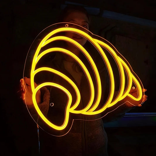 Person holding a glowing lemon yellow light shape like a croissant in a dark setting