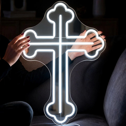 Person holding a white neon cross-shaped light in a dark setting