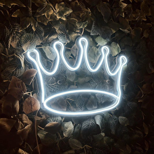 A white neon sign in the shape of a crown on the grass.