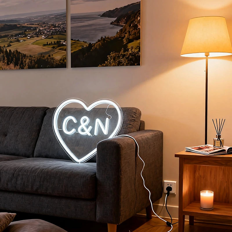 Heart-shaped neon sign with initials 'C&N' on a couch in a cozy living room.