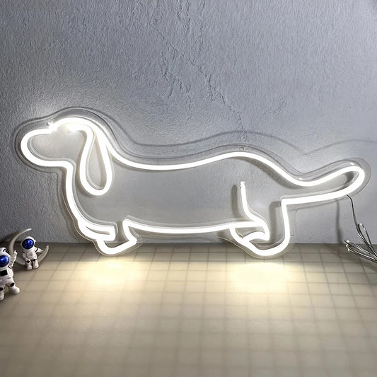 Neon white light shaped like a dachshund on a textured wall with small robot toys below.