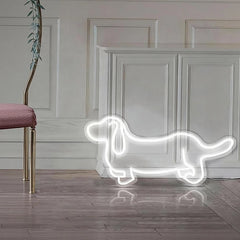 Neon white light shaped like a dachshund on a wooden floor with a decorative wall in the background.