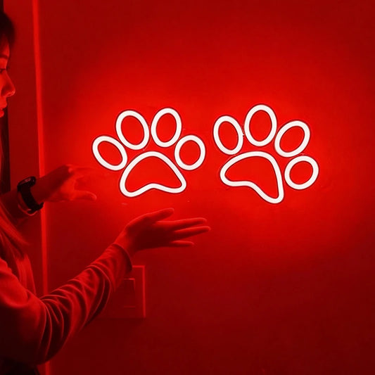 Neon sign of two red paw prints on a dark background