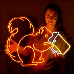 Woman holding a colorful squirrel neon sign in a dark room.