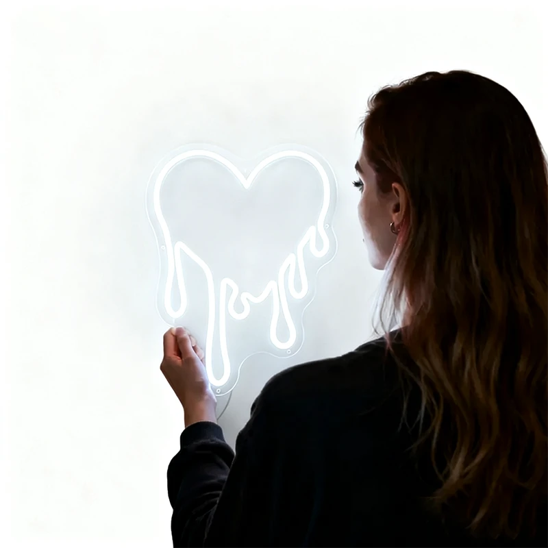 Person holding a white dripping heart neon sign against a white background