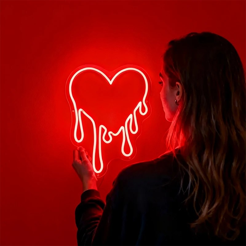 Person holding a red dripping heart neon sign against a white backgroundbackground