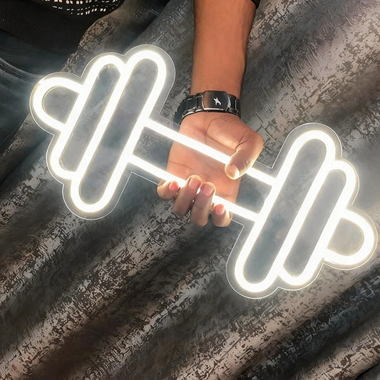Neon light shaped like a dumbbell held by a person against a textured dark background