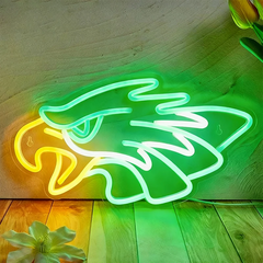Neon sign of an eagle on a wooden surface with flowers.