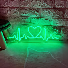 Neon with green light shaped like a heart with an ECG line on a textured wall.