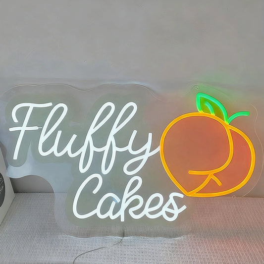 Neon sign with 'Fluffy Cakes' and a peach icon on a plain background