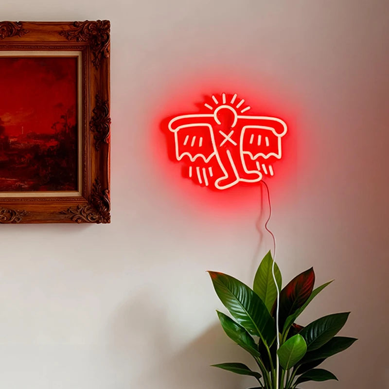 Red neon sign of a stylized keith haring flying man on a wall with a painting and plant in the background.