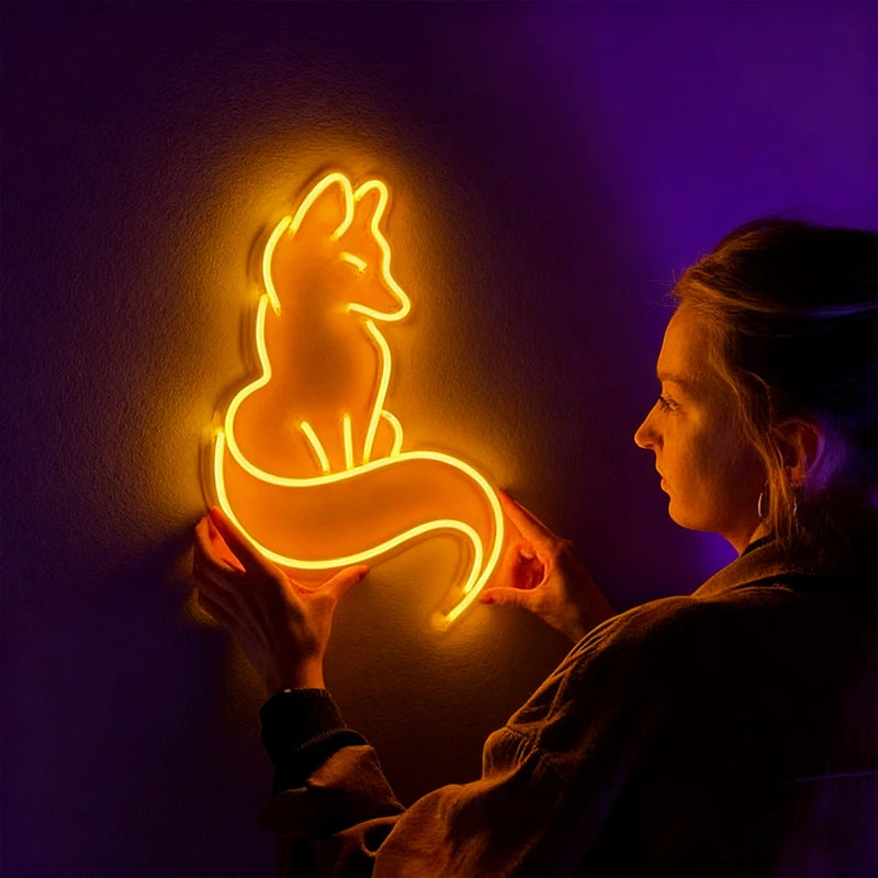 Person holding a glowing neon sign of a fox against a dark background