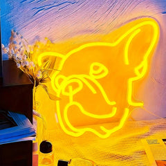 Neon sign of a dog's face on a textured wall with a vase and flowers in the foreground.