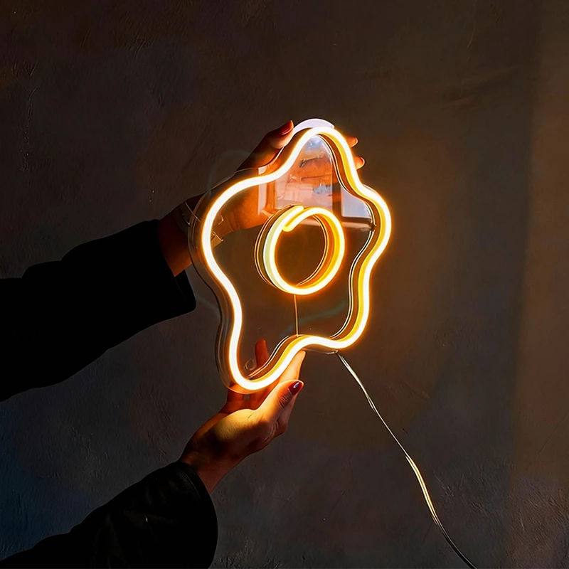 Neon light shaped like a fried egg held by a person against a dark background