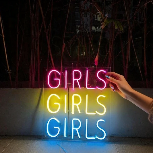 Neon sign with 'GIRLS GIRLS GIRLS' text held by a hand against a dark background.