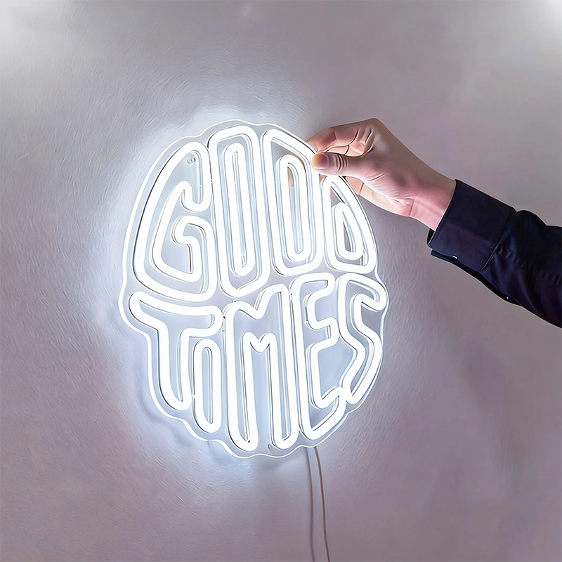 Neon sign with 'Good Times' text on a white wall, held by a hand.