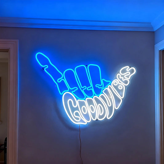Neon sign shaped like blue light fingers with white 'Good Vibes' text on a wall.