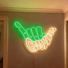 Neon sign shaped like green light fingers with warm white 'Good Vibes' text on a wall.