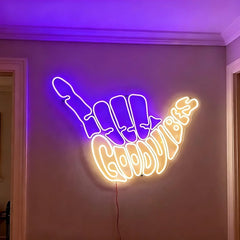 Neon sign shaped like a purple hand with warm white 'Good Vibes' text on a wall.
