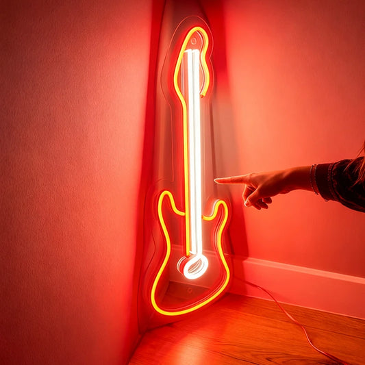 Neon guitar-shaped orange light on a wall with a hand pointing at it