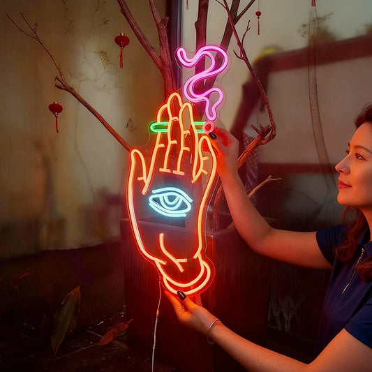 Neon sign of a hand with eye and smoking held by a person, with a blurred background.