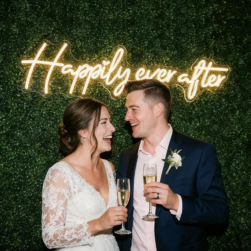 Couple celebrating with champagne in front of a 'Happily ever after' sign.