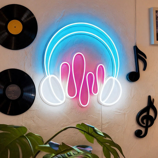 A neon wall sign shaped like headphones with hot pink sound wave details, glowing against a textured beige wall with vinyl records, music notes, and a plant visible.