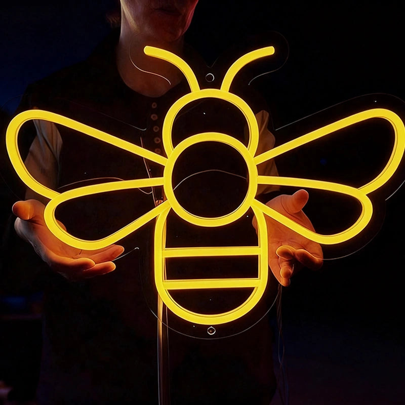 Woman holding a lemon yellow color honeybee neon sign in a dark background.
