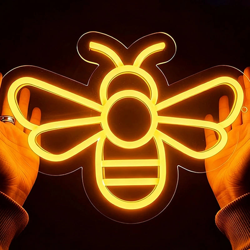 Neon bee light held between two hands against a dark background