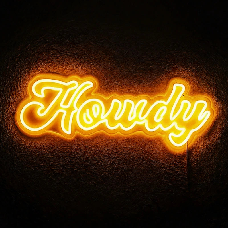 A lemon yellow 'Howdy' neon sign glowing on a wall.