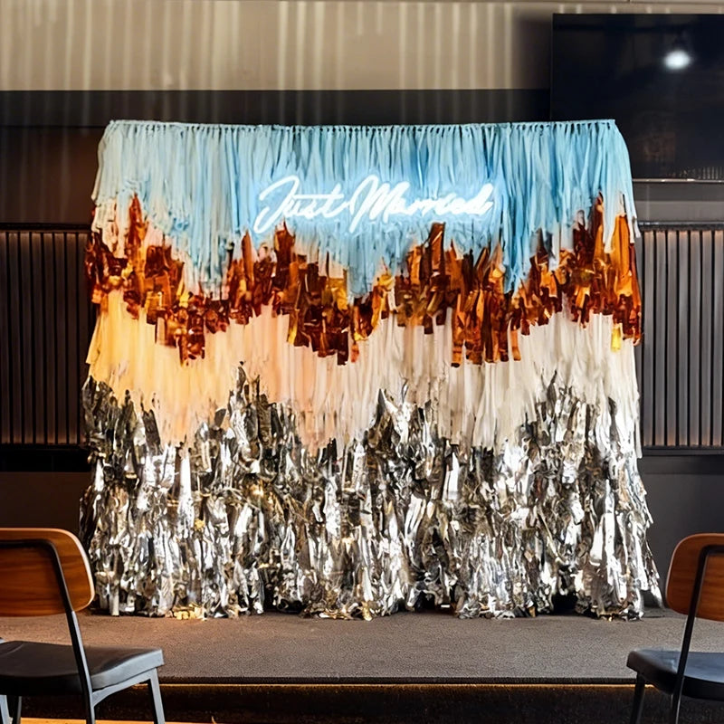 Decorative backdrop with 'Just Married' sign and tinsel design in a room setting.