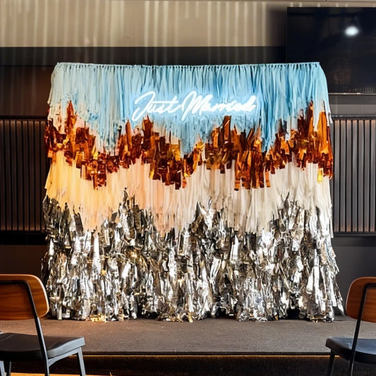 Decorative backdrop with 'Just Married' sign and tinsel design in a room setting.