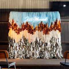 Decorative backdrop with 'Just Married' sign and tinsel design in a room setting.