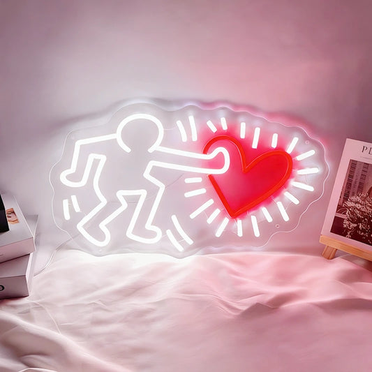 Neon light shaped like a person with a heart on a bed