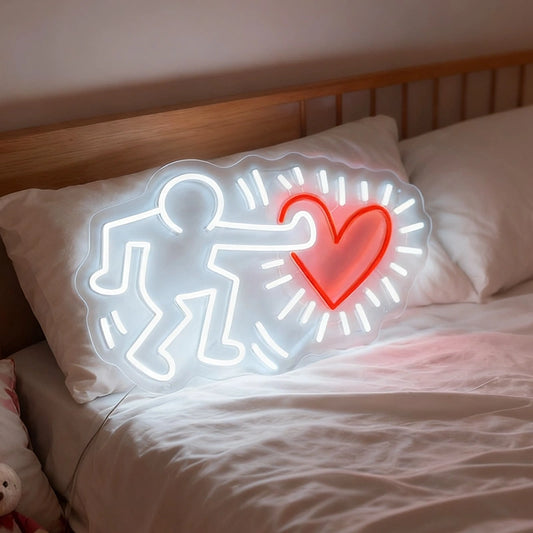 Neon sign of a person holding a heart on a pillow with bedding in the background