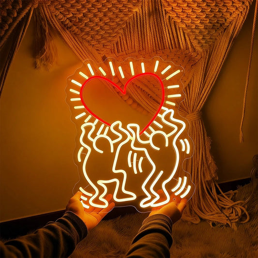 Neon light shaped like a heart with two people embracing, held against a textured wall.