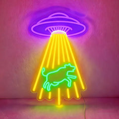 Neon sign with a purple UFO and green cow design on a pink background