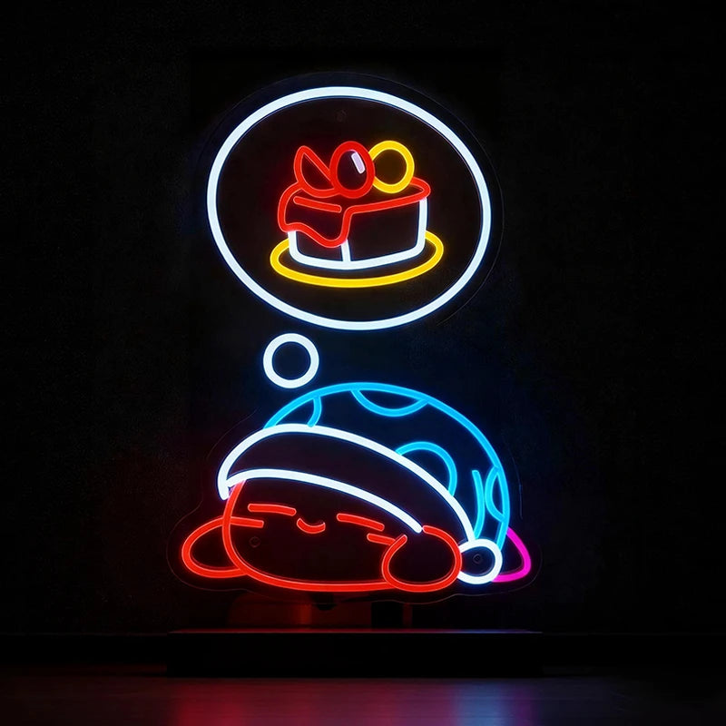 Neon sign of a kirby cartoon character with a cake in a thought bubble on a black background