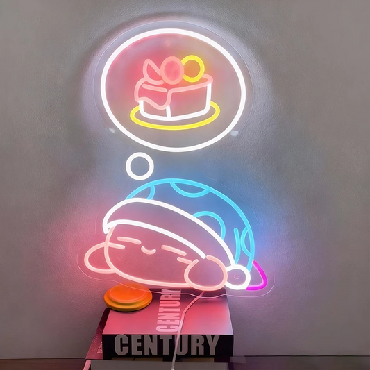 Neon sign of a kirby cartoon character with a cake in thought bubble on a gray background