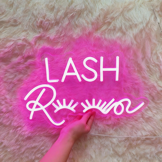 Neon sign with 'LASH' and 'Room' text on a fluffy pink surface