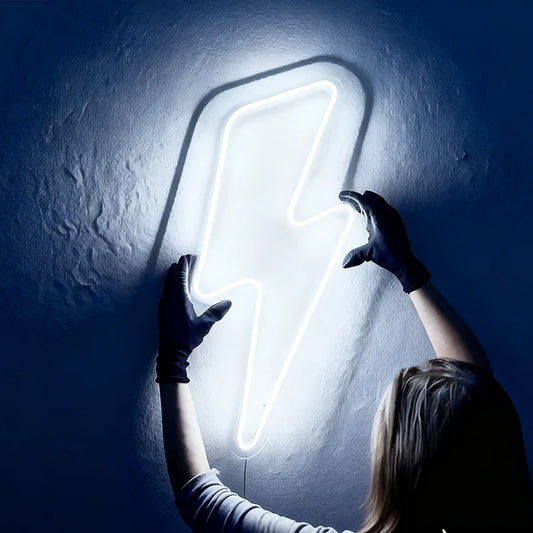 White neon lightning bolt sign held by a person against a dark wall